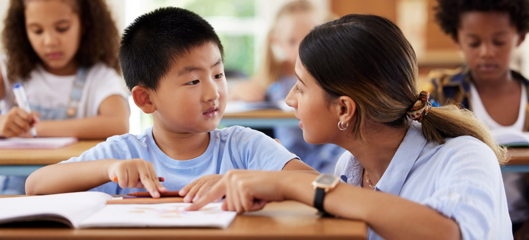 Young boy working one-on-one with teacher in classroom